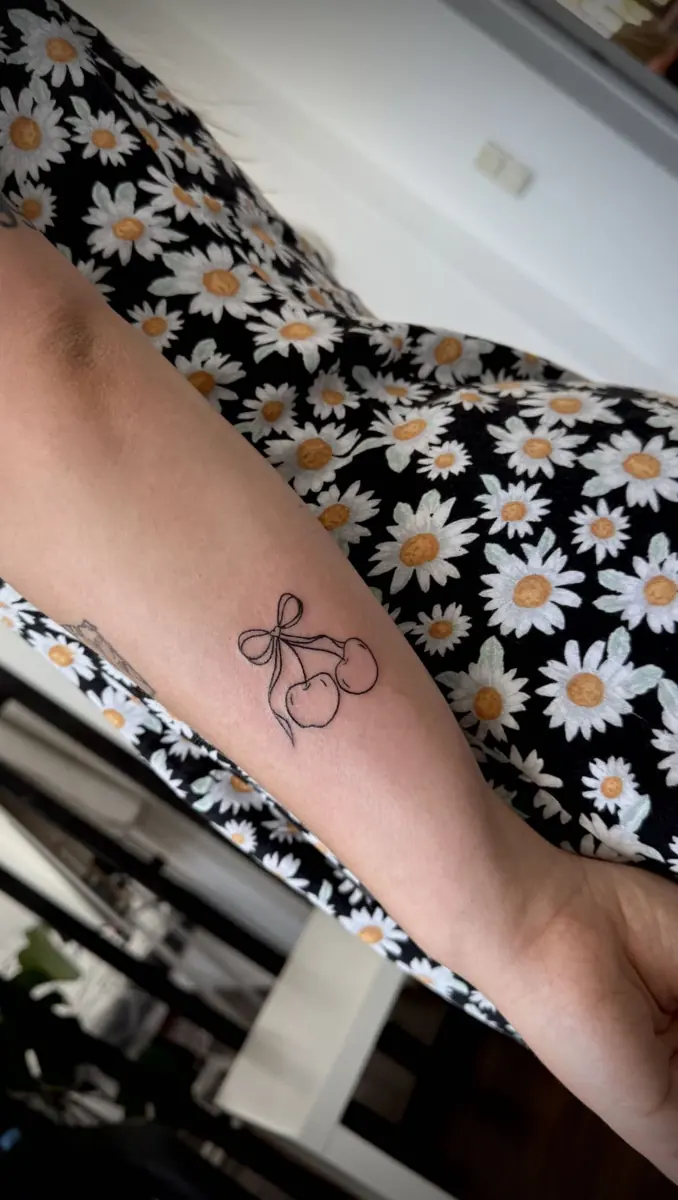 Minimalistyczny tatuaż wiśnie z kokardką